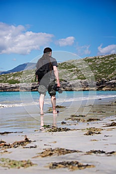 Young male photographer with dreadlocks at a sunny white sand beach