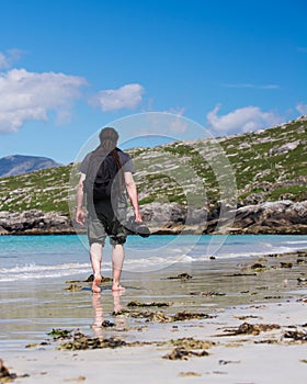 Young male photographer with dreadlocks at a sunny white sand beach, Luskentyre, Isle of Harris, Hebrides, Scotland