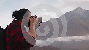 A young male photographer in the mountains takes pictures of the landscape