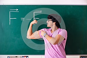 The young male physic standing in front of the green board