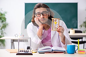 Young male physicist teacher in time management concept