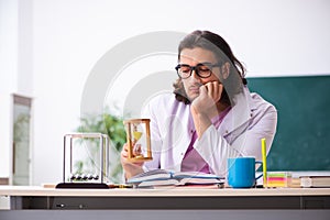 Young male physicist teacher in time management concept