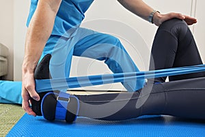 A young male physiotherapist helping a girl with stretching exercises