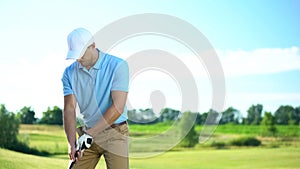 Young male player ready to hit ball at golf course, attentive golfer competition