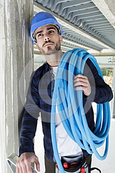 Young male plumber carrying blue water pipe