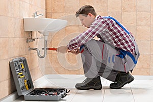 Young Male Plumber Fitting Sink