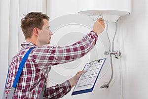 Male Plumber Adjusting Temperature Of Electric Boiler