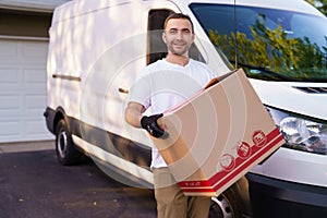 Young male postal delivery courier man in front of cargo van delivering package