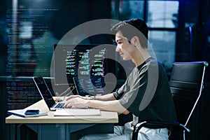 Young male programmer working with tablet and screen displaying code. Modern tech office setup, great for software, coding, IT