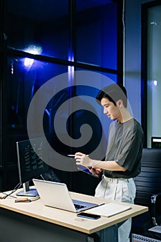 Young male programmer working with tablet and screen displaying code. Modern tech office setup, great for software, coding, IT