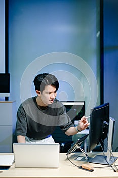 Young male programmer working with tablet and screen displaying code. Modern tech office setup, great for software, coding, IT