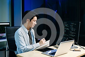 Young male programmer working with tablet and screen displaying code. Modern tech office setup, great for software