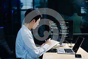 Young male programmer working with tablet and screen displaying code. Modern tech office setup, great for software