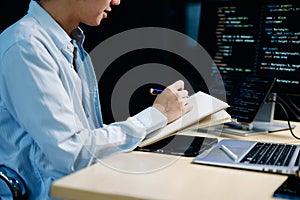 Young male programmer working with tablet and screen displaying code. Modern tech office setup, great for software