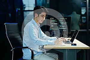 Young male programmer working with tablet and screen displaying code. Modern tech office setup, great for software