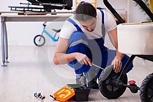 Young male repairer repairing perambulator indoors