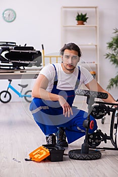 Young male repairer repairing perambulator indoors