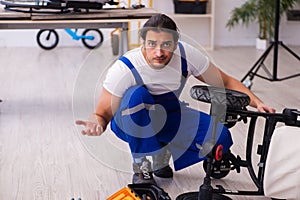 Young male repairer repairing perambulator indoors