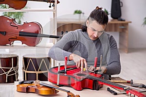 Young male repairman repairing guitar