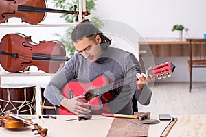 Young male repairman repairing guitar