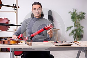 Young male repairman repairing guitar