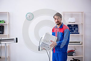 Young male repairman repairing oven at workshop