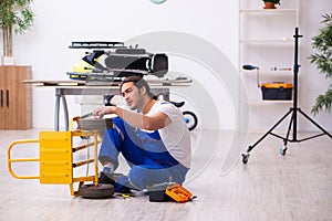 Young male repairman repairing trolley indoors