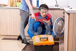 Young male repairman repairing washing machine