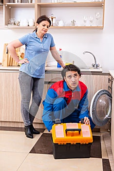 Young male repairman repairing washing machine