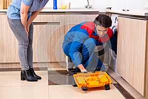 Young male repairman repairing washing machine