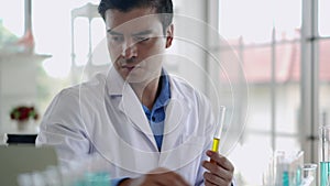 Young male researcher analyzing liquid in tube at laboratory