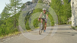 Young male road cyclist having fun pedalling his bike up a steep asphalt road.