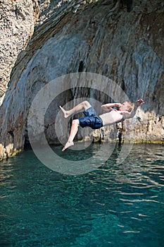 Young male rock climber jumping from a cliff