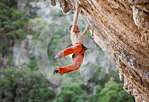 Young male rock climber after jumping and gripping small handholds photo