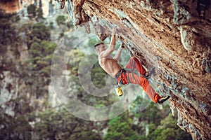 Young male rock climber on overhanging wall. Rock climbing on natural cliff