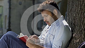 Young male romantic plunged with head into world of printed word, reading book