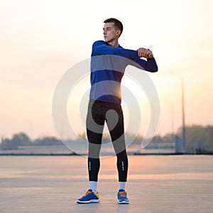 Young Male Runner Stretching Before Run at Sunset. Healthy Lifestyle and Sport Concept.
