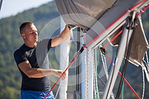 A young male sailor setting sail on his yacht. Sport.