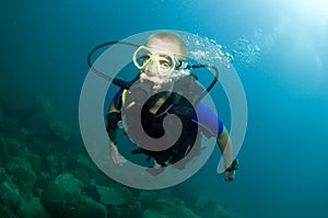 Young male scuba diver swims over reef