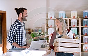 Young shop assistant serving an attractive woman in a zero waste shop.