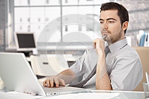 Young male sitting at desk working on laptop