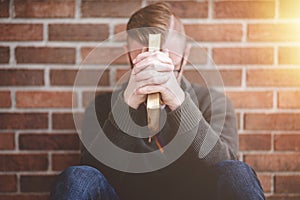 Young male sitting on the ground and holding the bible in his hands