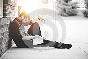 Young male sitting on the ground and holding the bible in his hands