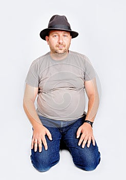 Young male sitting and holding a hat on head