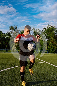 Young male soccer player juggles a ball on a soccer field