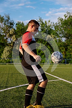 Young male soccer player juggles a ball on a soccer field