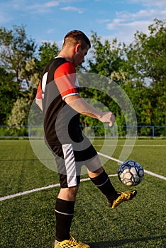 Young male soccer player juggles a ball on a soccer field