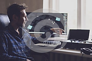 A young male sound engineer working on a new music project in the studio