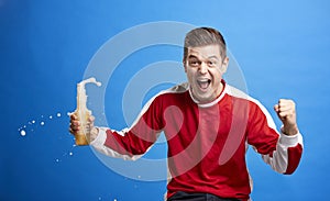 Young male sports fan celebrating with a spilling drink