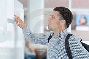 young male student checking notice board